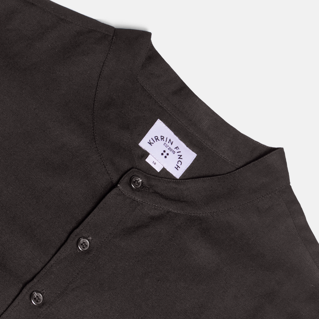 Close-up of a black banded shirt with a Kirrin Finch logo on a light gray background. Color: Black