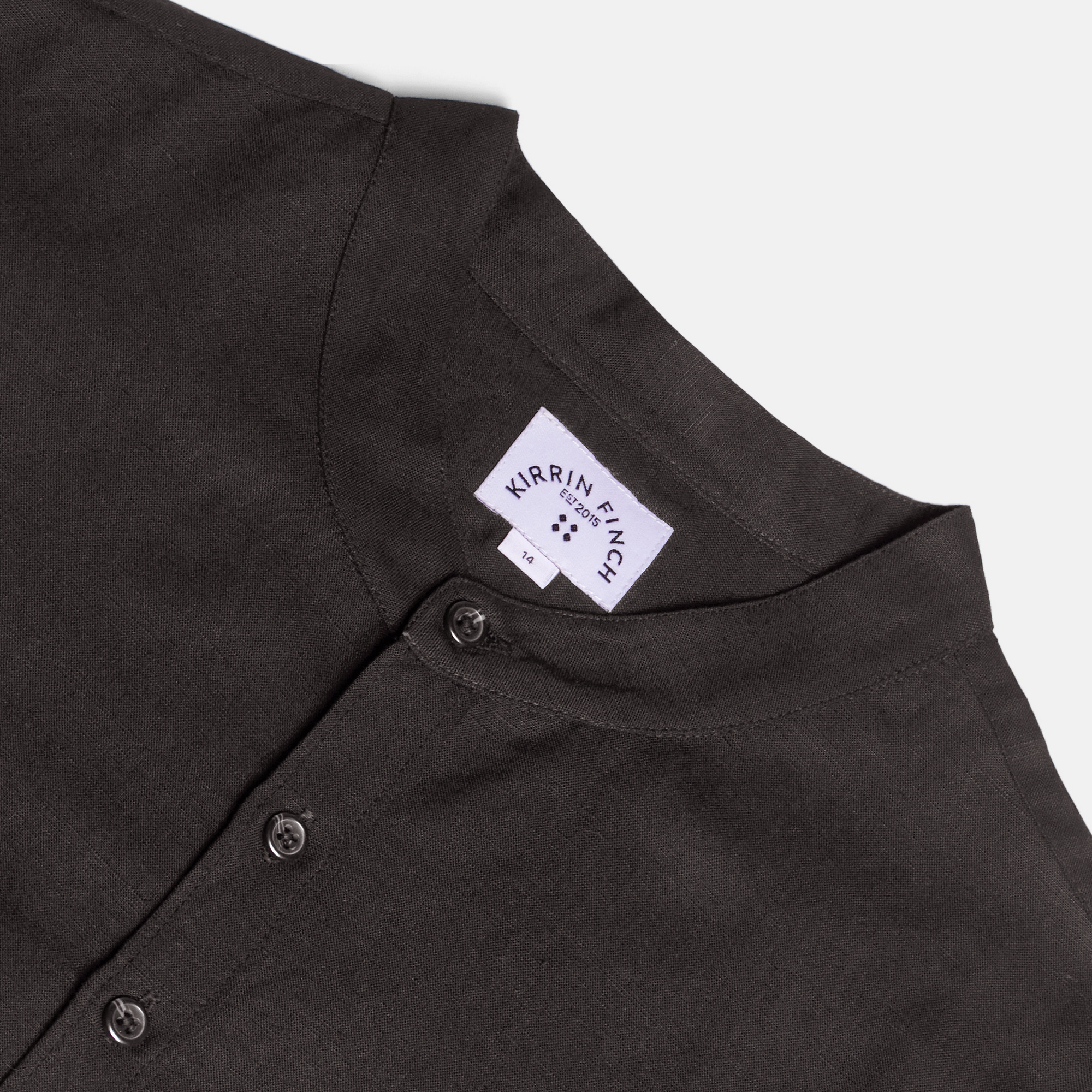 Close-up of a black banded shirt with a Kirrin Finch logo on a light gray background. Color: Black