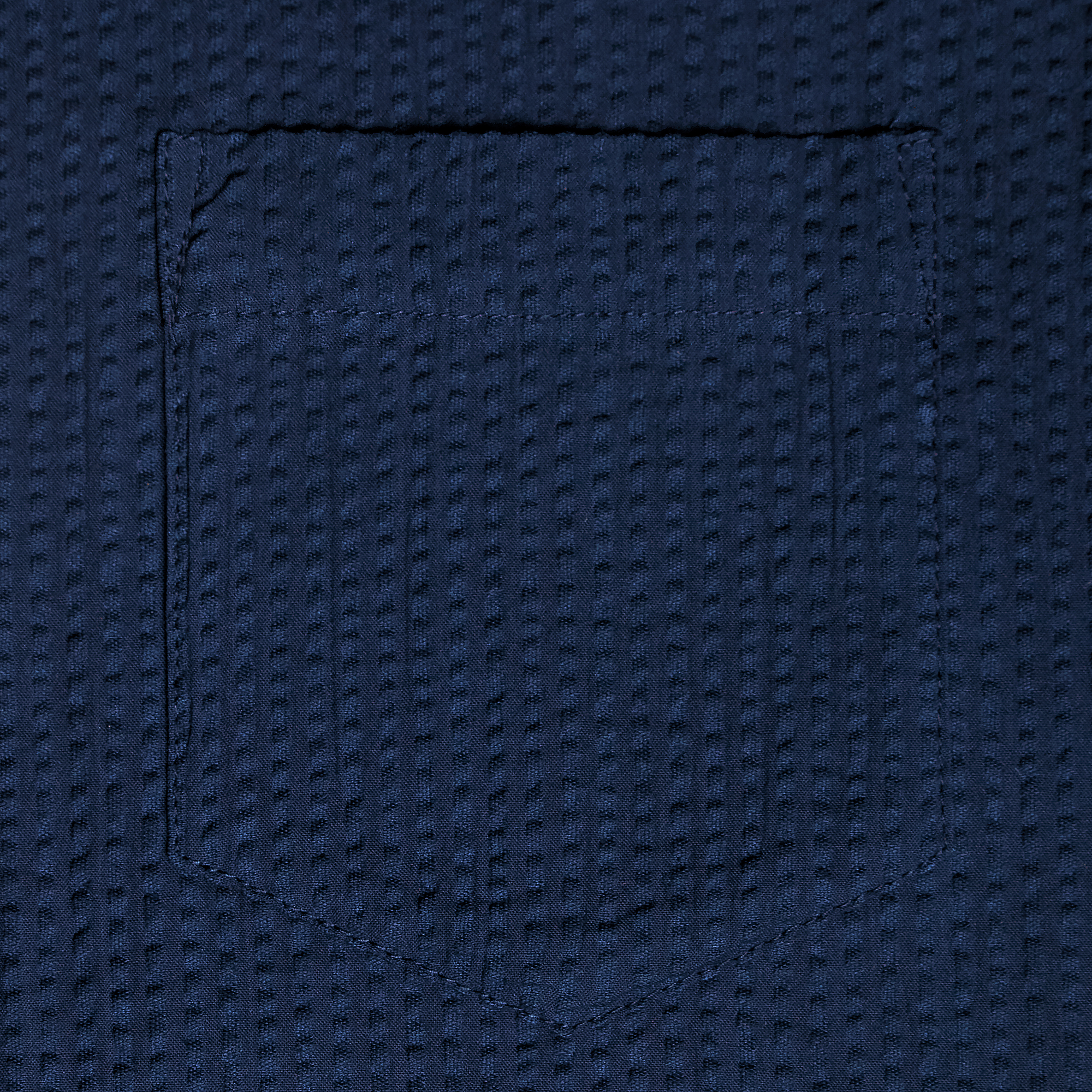 Close-up of a textured navy blue fabric with a pocket made by Kirrin Finch. Color: Azul