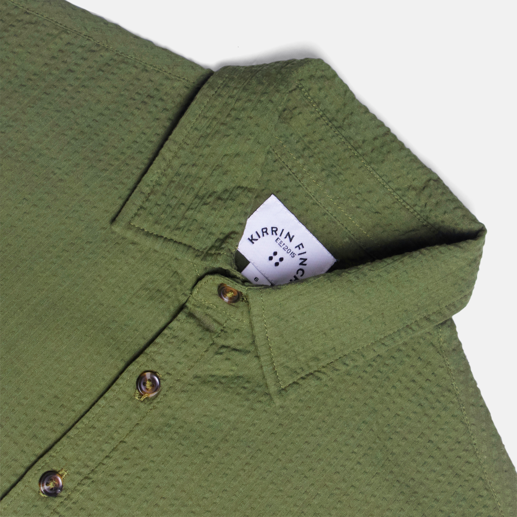 Green short sleeve shirt on a white background. Made by Kirrin Finch. Color: Nopales