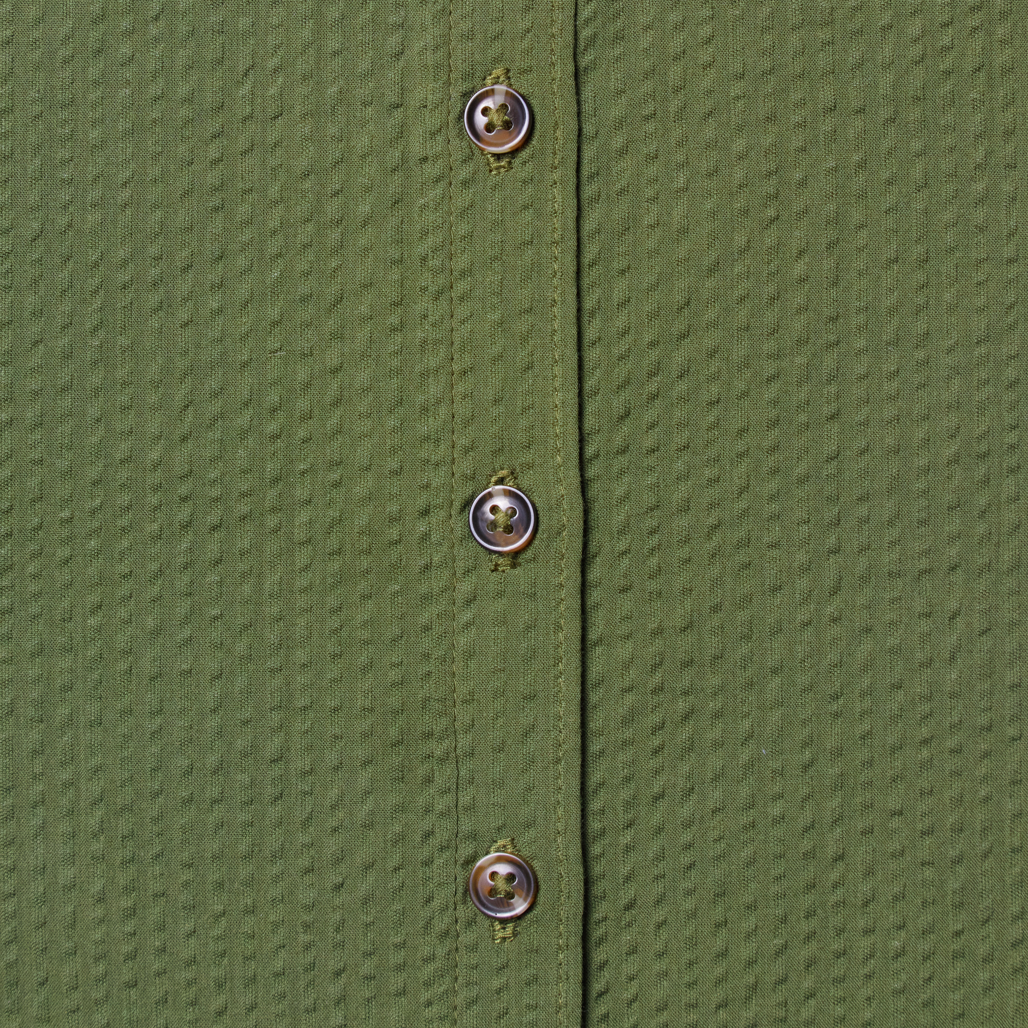 Close-up of a green textured shirt with buttons. Color: Nopales
