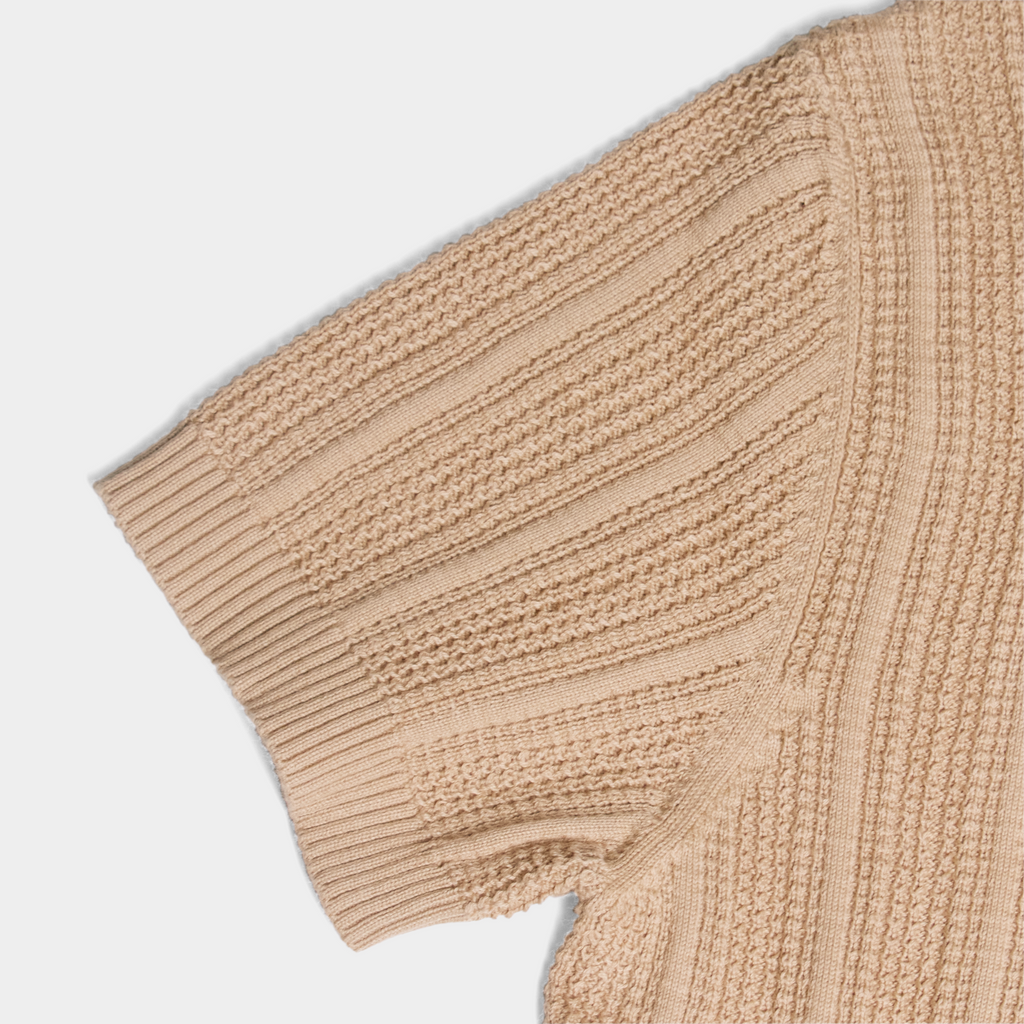 Flat lay shot of a beige cardigan highlighting the stitching detail. Color: Camel