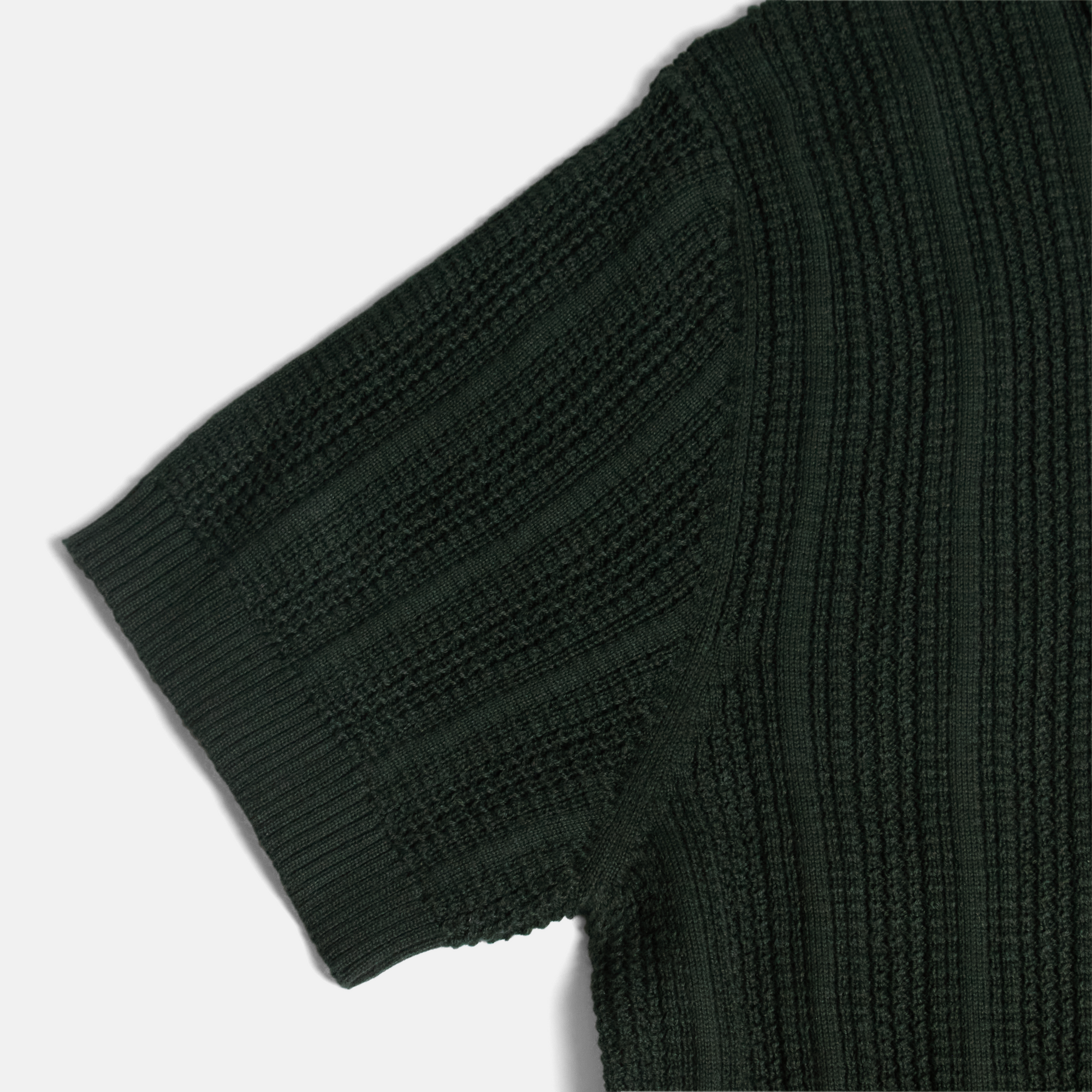 Flat lay shot of a dark green cardigan highlighting the stitching detail. Color: Evergreen