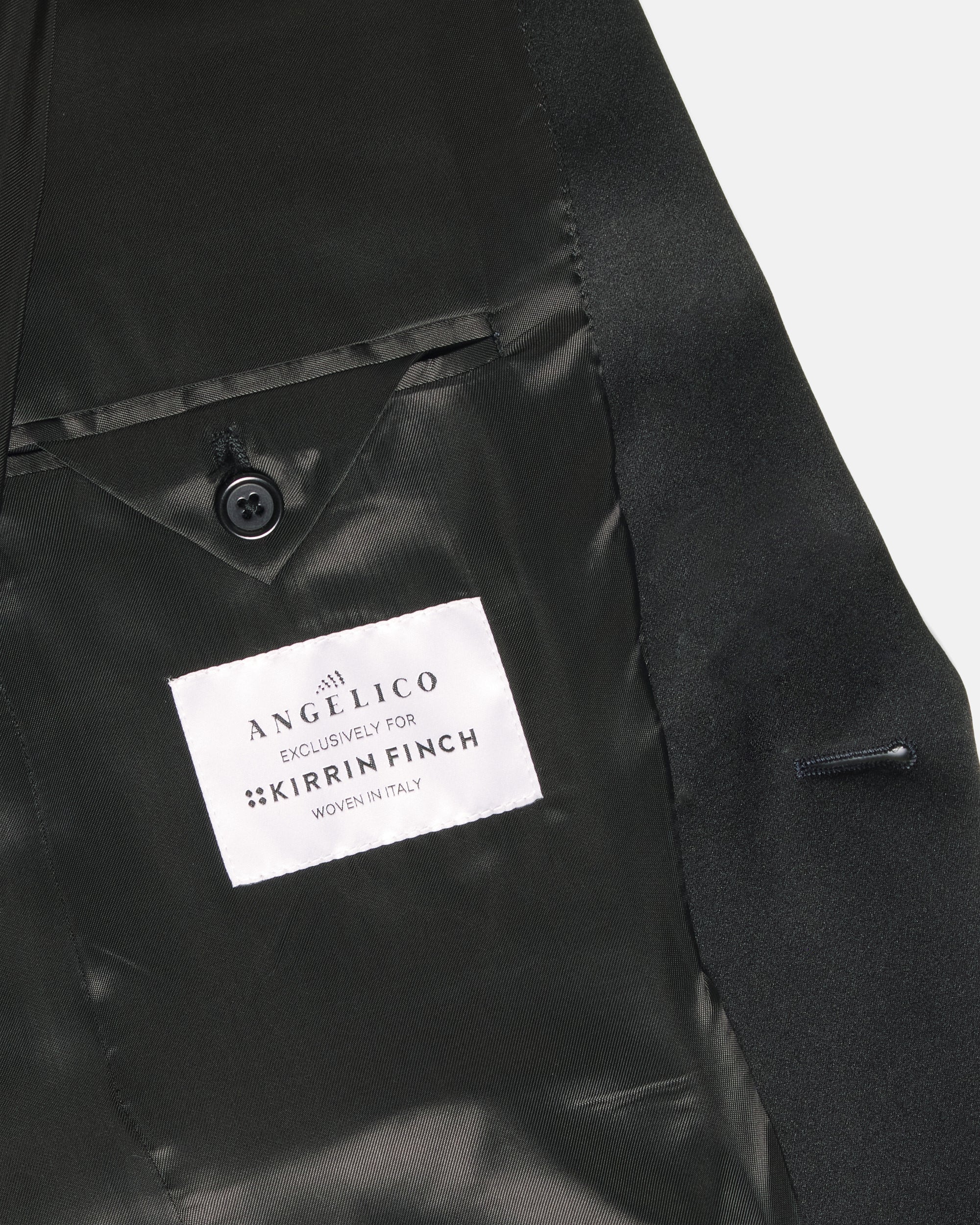 Close-up of a black satin lapel with a white fabric brand label. Color: Sapphire Brocade