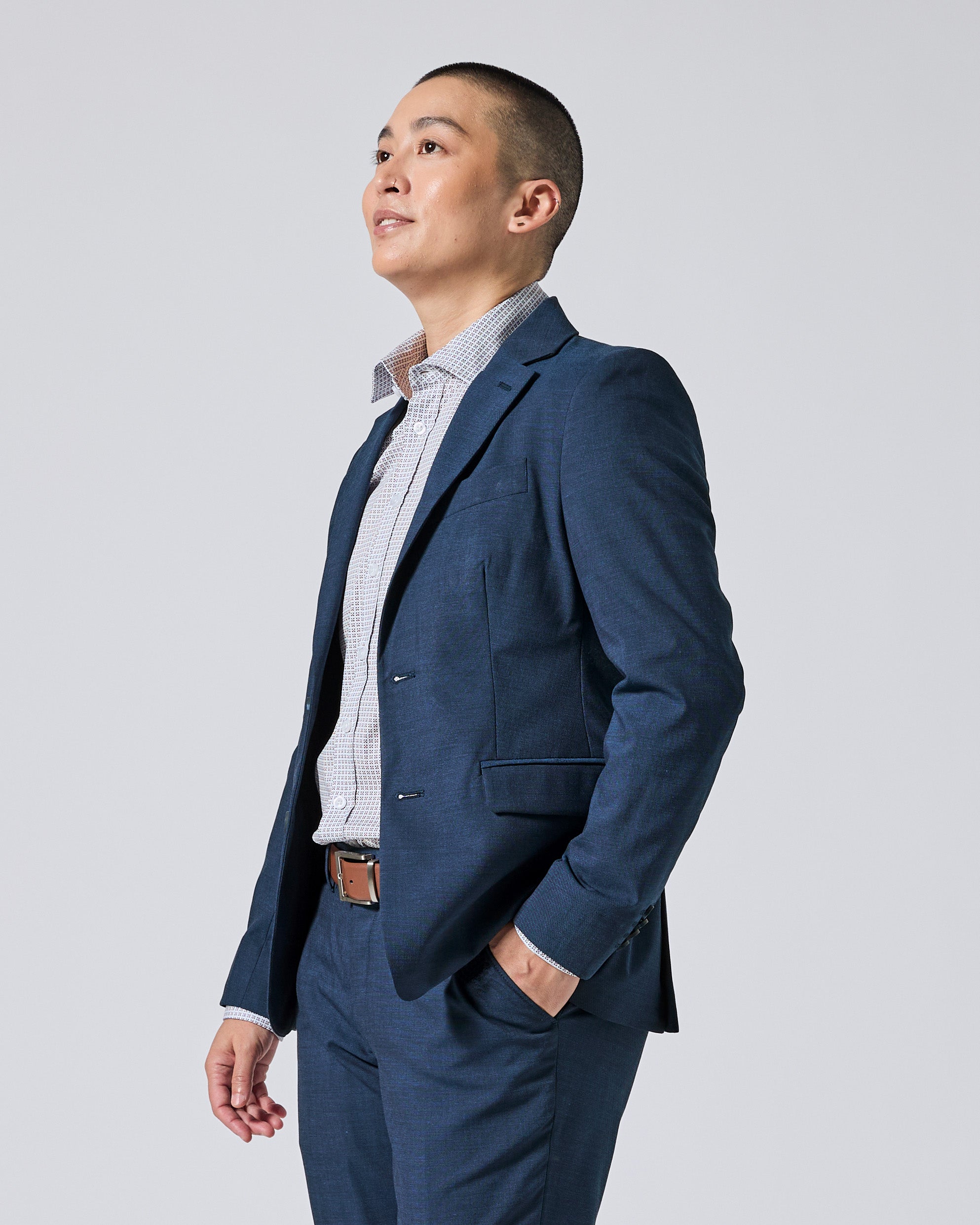 Person wearing an Atlantic blue suit jacket and matching trousers, styled with a light blue and white checkered dress shirt, standing against a solid light gray background. Color: Atlantic Blue