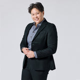 Person wearing a Phantom Green Twill Scout blazer over a blue patterned button-down shirt, paired with black trousers, standing against a solid light gray background. Color: Phantom Green Twill