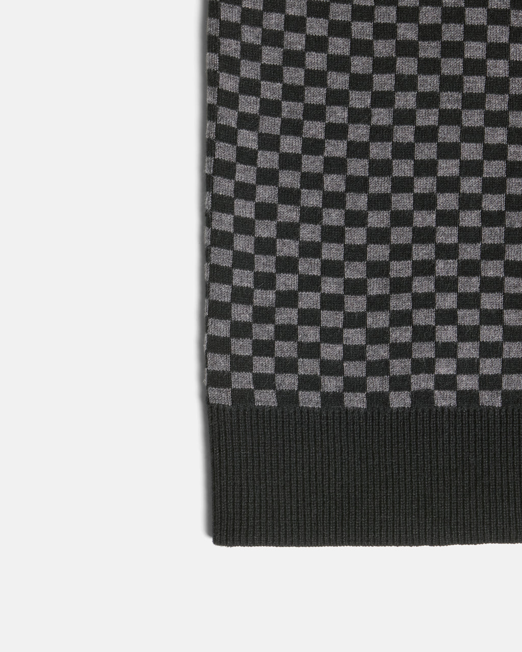 Close-up of a black and gray checkerboard knit fabric with a ribbed black border, shown on a light gray background. Color: Shadow Checker