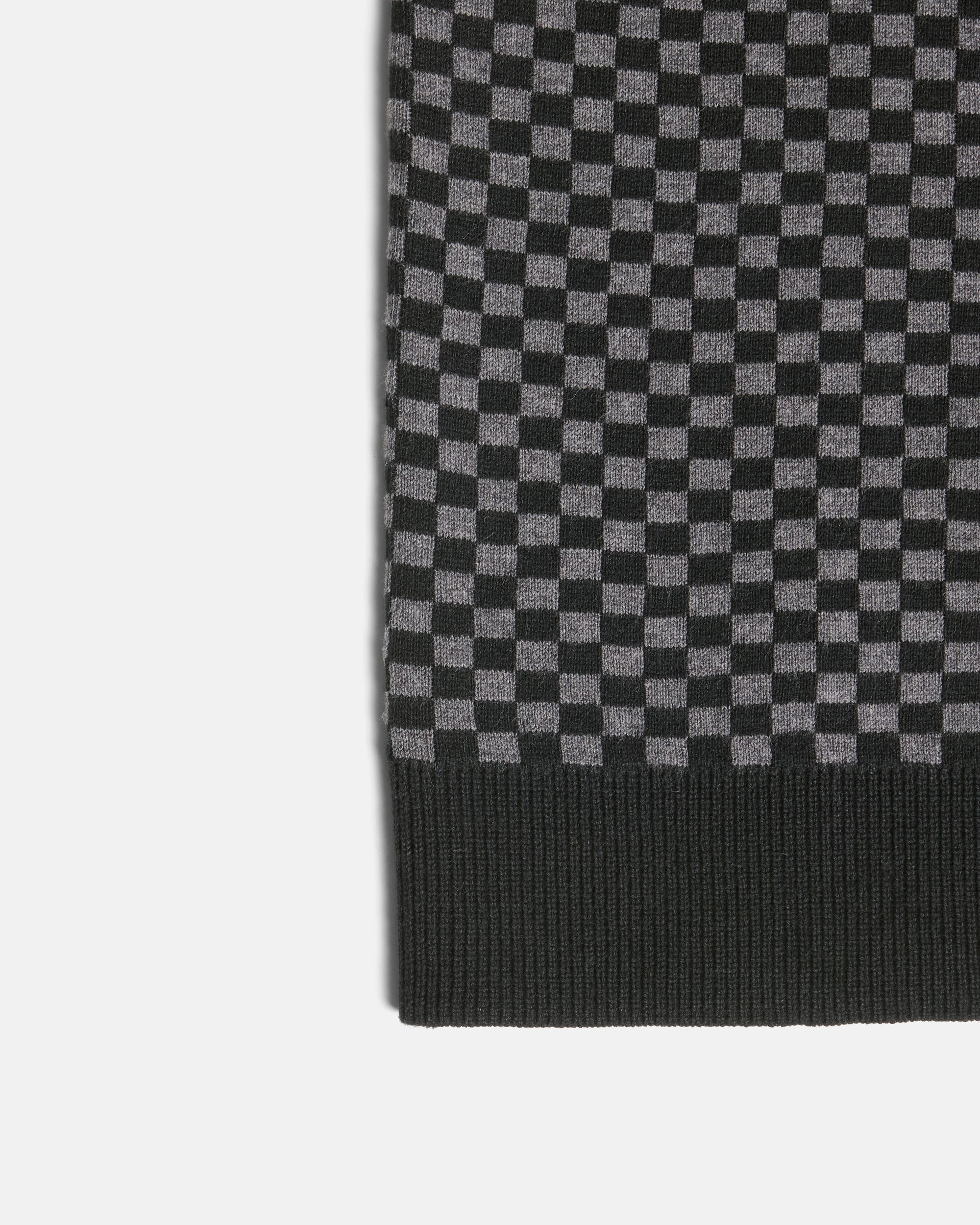 Close-up of a black and gray checkerboard knit fabric with a ribbed black border, shown on a light gray background. Color: Shadow Checker