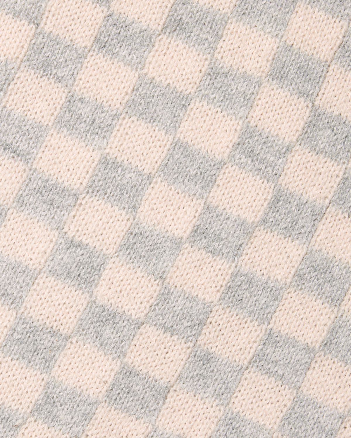 A close-up of a knit fabric with a soft checkerboard pattern in pale blush pink and light gray. Color: Saltstone Checker