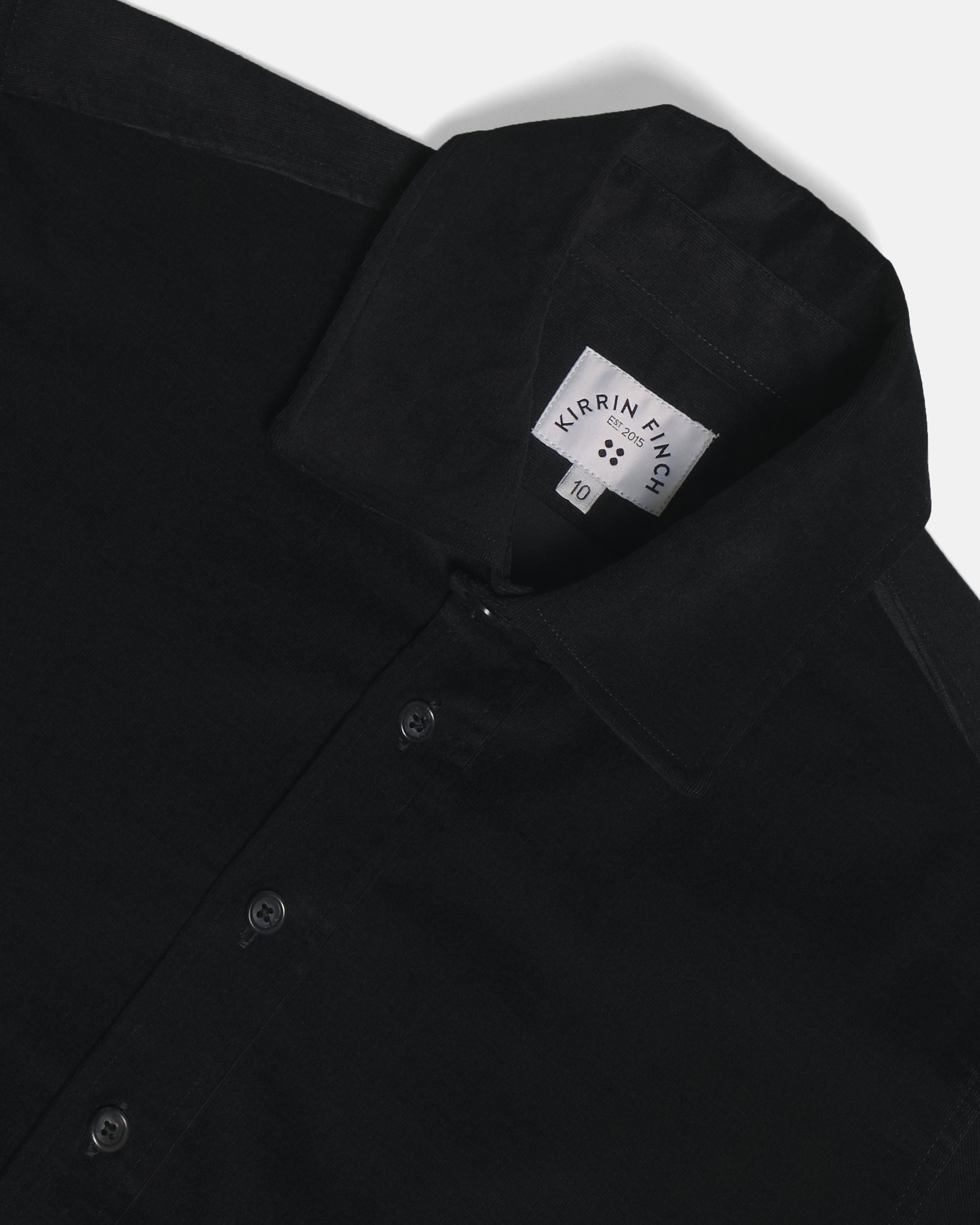 Close-up of a black button-down shirt collar laid flat on a light gray background. Color: Shadow Corduroy