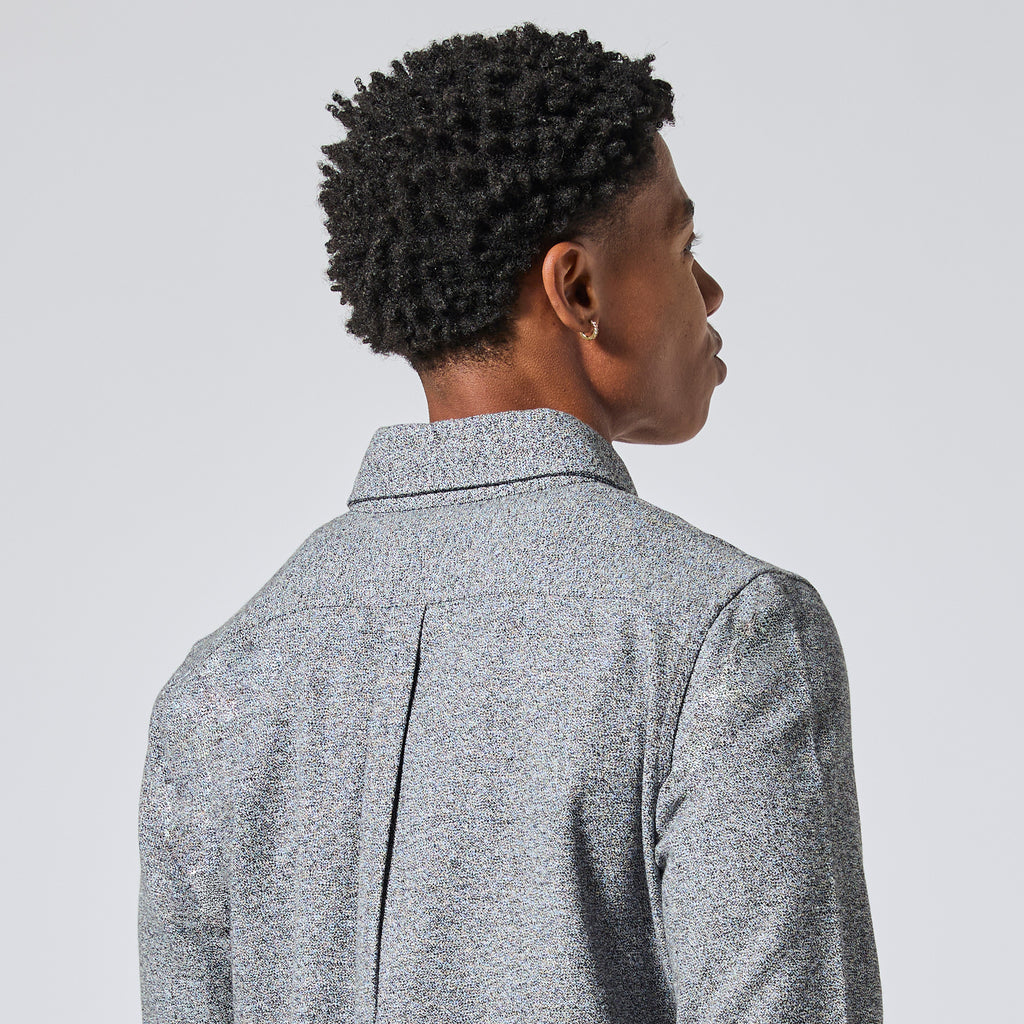 Model with short, curly black hair is shown from the back wearing a textured gray collared shirt jacket against a light gray studio background. Color: Static