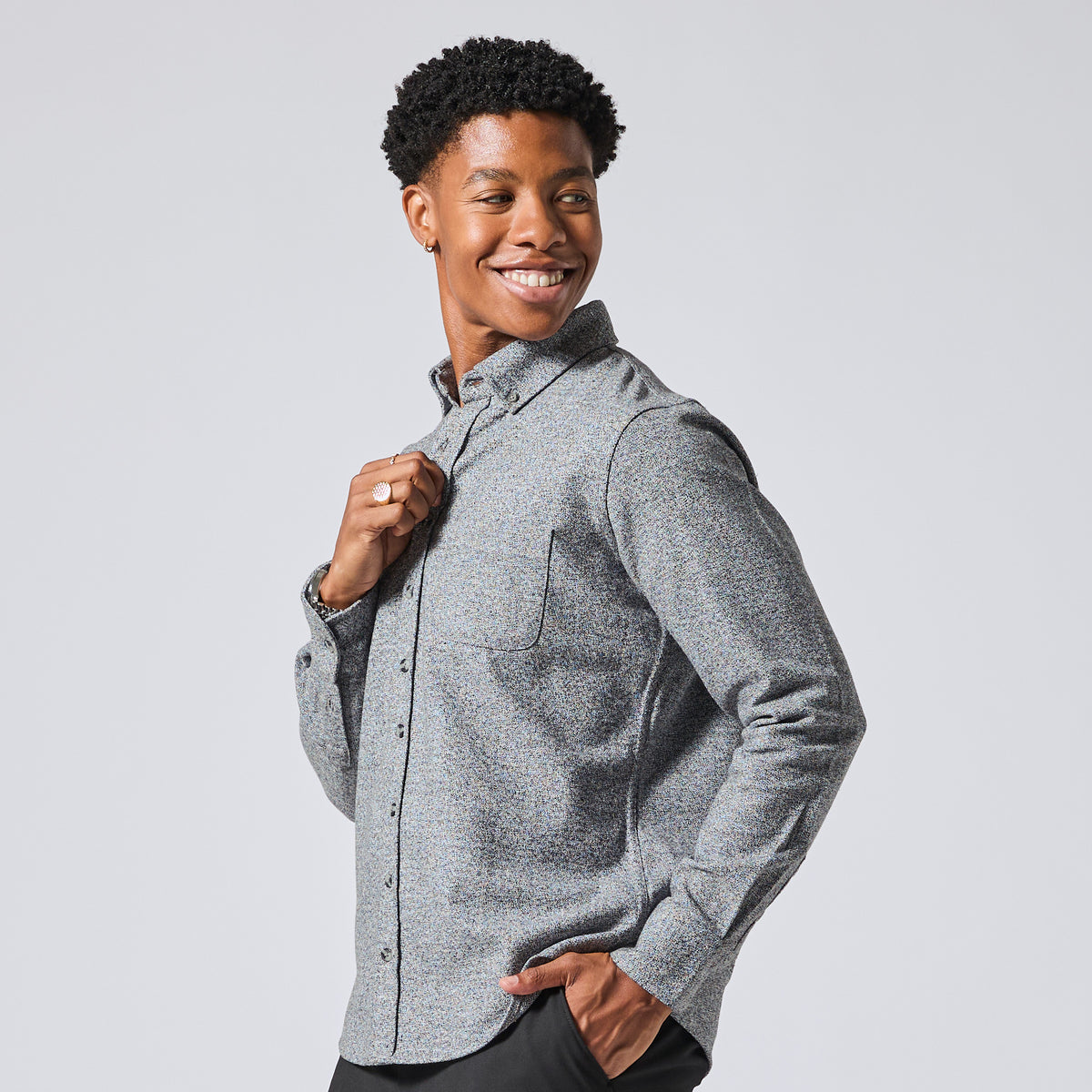 Smiling model wearing a textured gray long-sleeve button-down shirt, posing against a light gray studio background. Color: Static