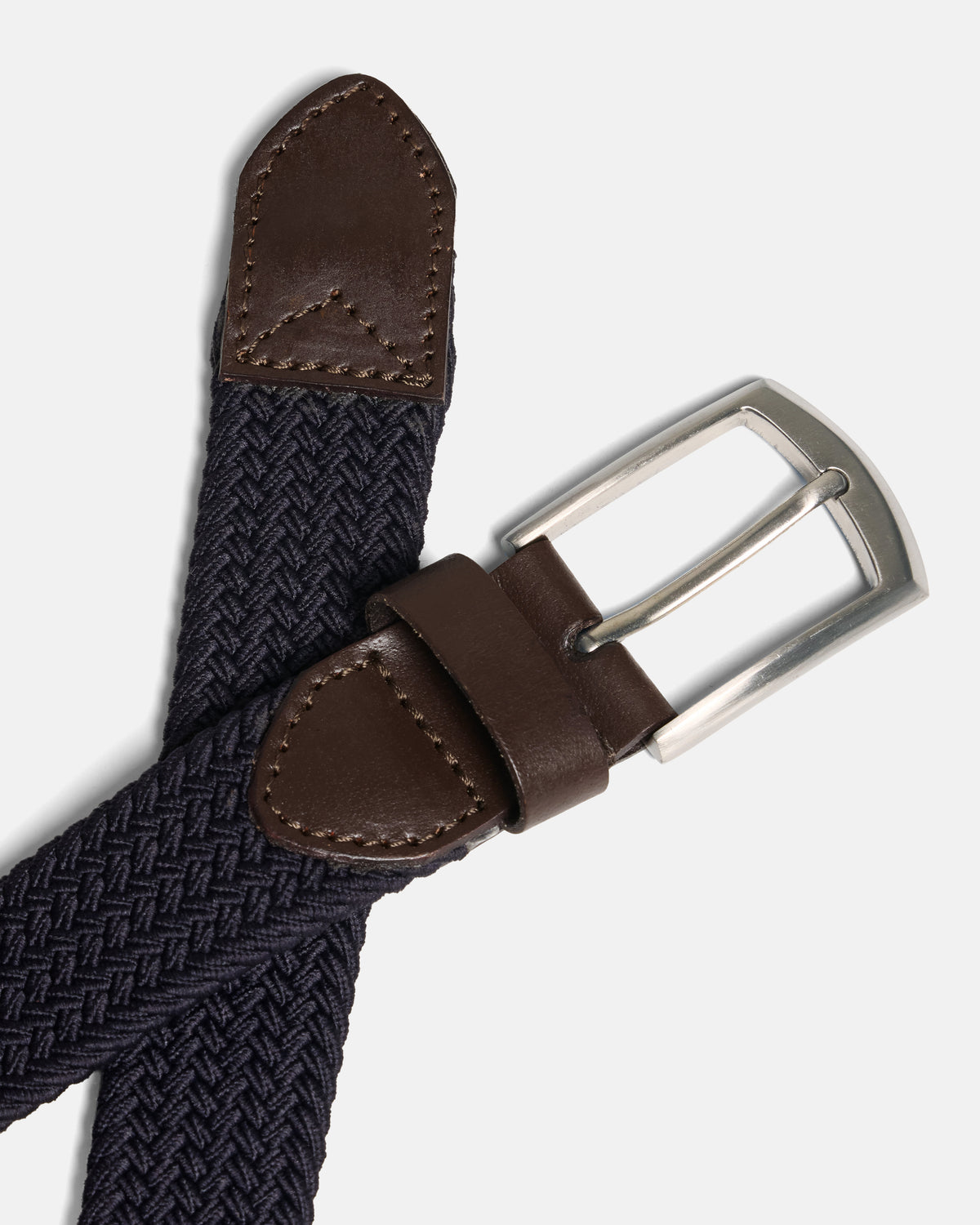 A close-up of a woven belt with a dark navy blue braided strap, brown leather accents, and a silver metal buckle, set against a light gray background. Color: Navy