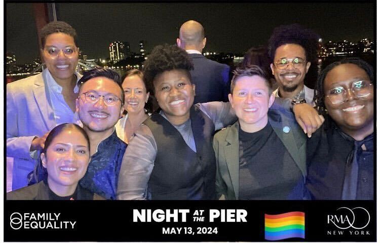 Group of people posing together with a cityscape background at Night at the Pier event.