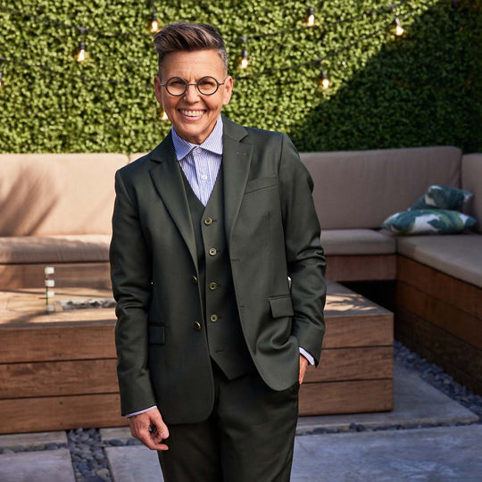 androgynous model in outdoor resort setting wearing georgie olive suit with navy and white striped dress shirt. Entire outfit by Kirrin Finch.