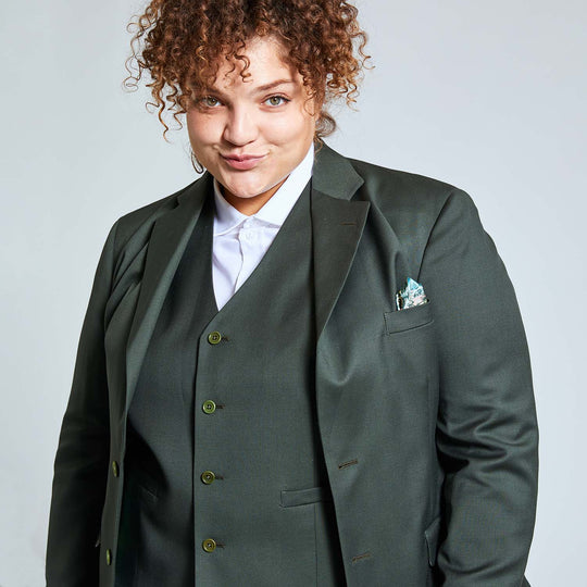 Androgynous model wearing the Georgie Olive blazer and vest, with complimentary golf leaf print pocket square. A white dress shirt and piercing hazel eyes complete the look.