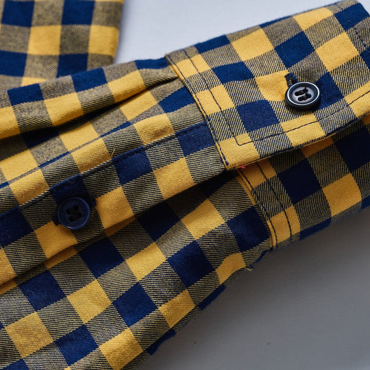 Blue button details on the cuff and sleeve of a yellow and navy buffalo check button down shirt
