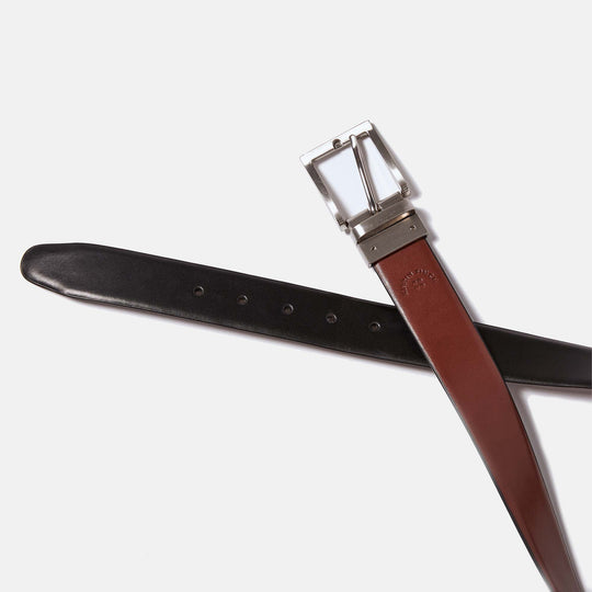 Reversible leather belt curved to show brown leather side at buckle and black leather side at its end tip