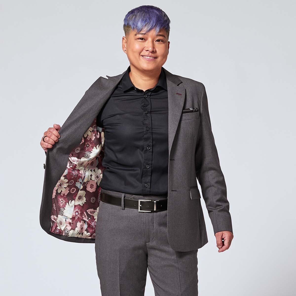 Androgynous model wearing georgie charcoal blazer, exposing colorful burgundy floral blazer lining
