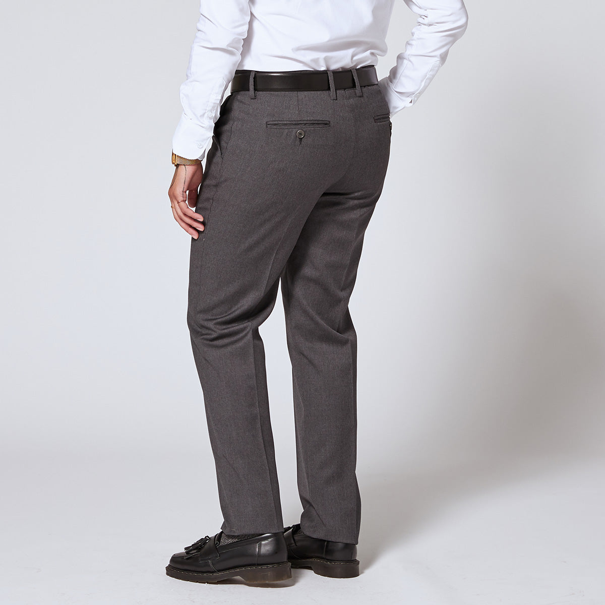 Back view of the Georgie charcoal dress pants paired with the reversible belt by Kirrin Finch. Charcoal buttons are under the back pocket slit as a secondary enclosure. Color: Charcoal