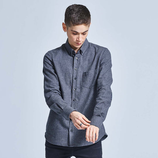 Androgynous model fixing sleeve of charcoal flannel on neutral background