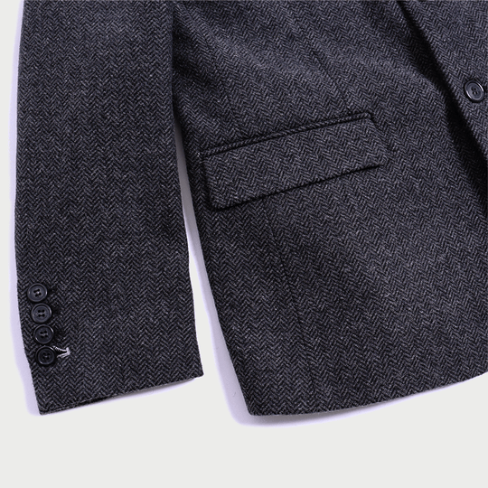 Close shot of charcoal tweed blazer by itself showing off texture and sleeve buttons