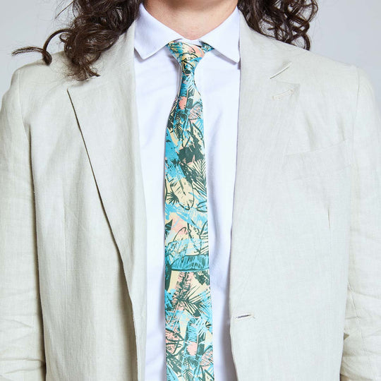 Model wearing Kirrin Finch skinny multicolored leaf print tie on a white dress shirt and sand linen blazer