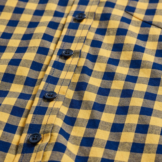 A close-up of a series of navy buttons on a buffalo check shirt