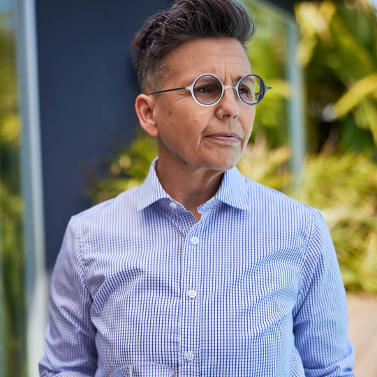 Model wearing Navy and white grid shirt with white round glasses staring sternly off into the distance