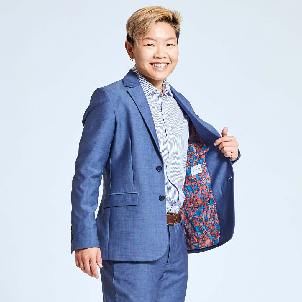 Androgynous person modeling slate blue suit, opening blazer to reveal colorful lining by Lisa Congdon