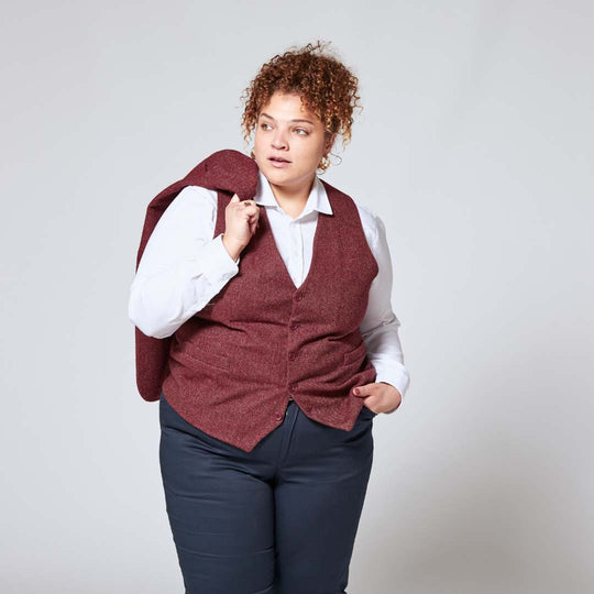 Person modeling Tweed Burgundy Vest with matching tweed blazer slung over her shoulder. Outfit completed with white dress shirt and navy pants