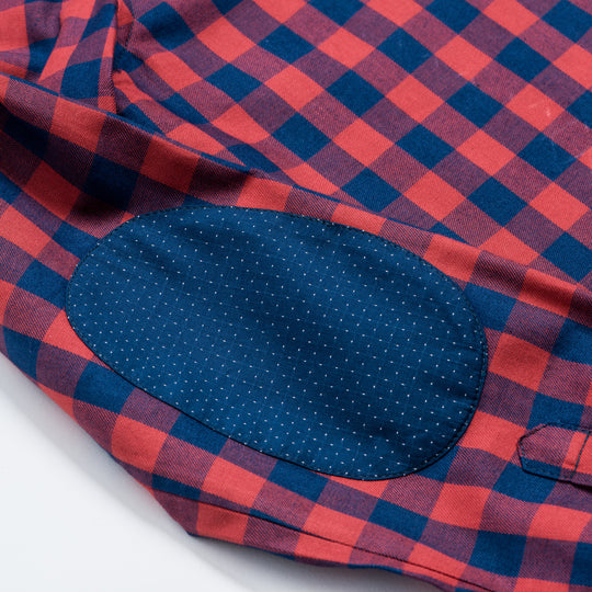 zoomed in shot of polka dot elbow patch on red and navy check flannel